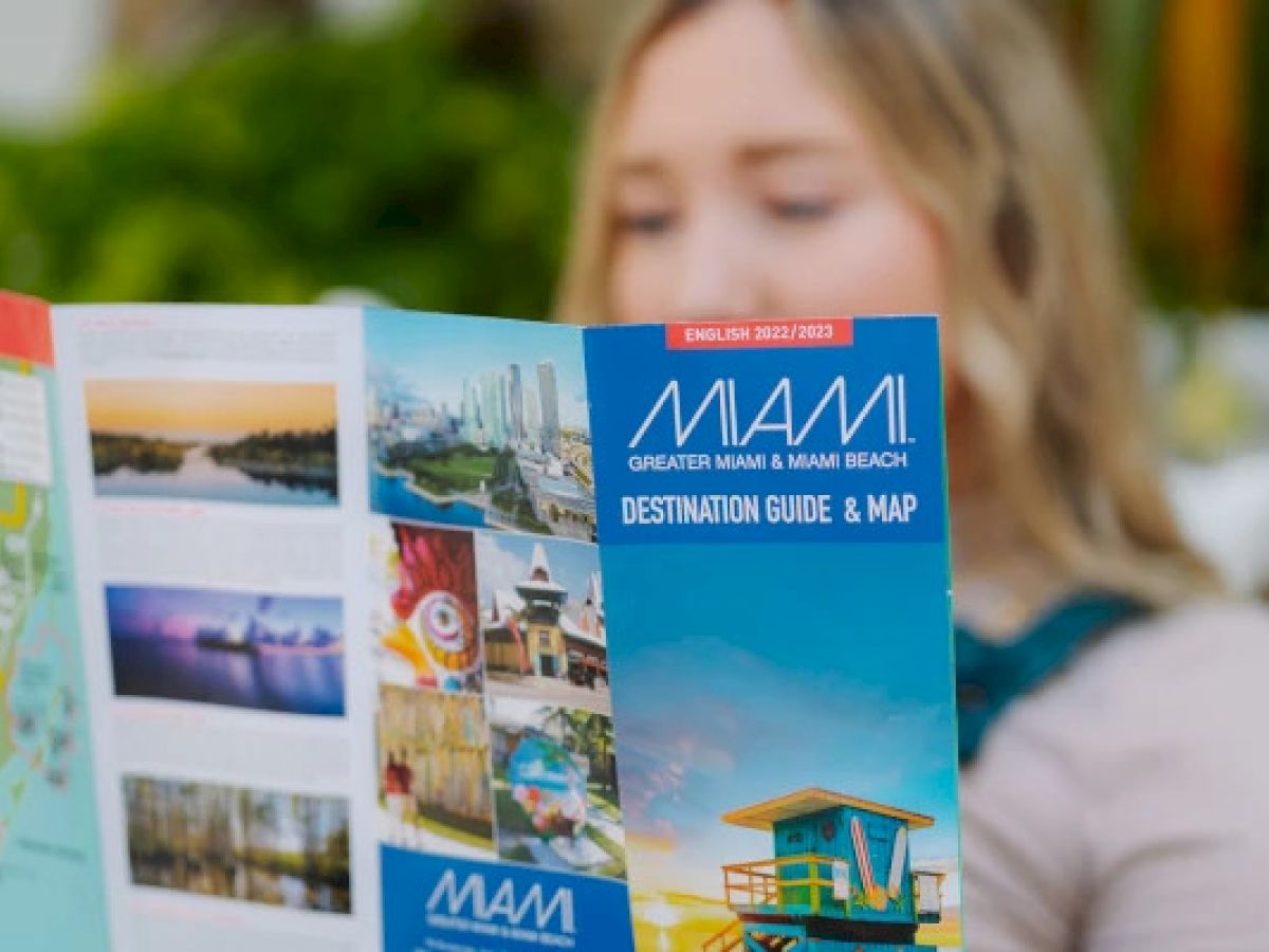 A person is holding a "Miami Destination Guide & Map" featuring colorful images and maps.